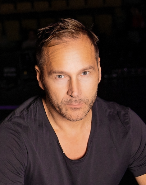 Portrait of Per Lidén, co-founder and partner of Xventure Group, wearing a black t-shirt against a dark background.